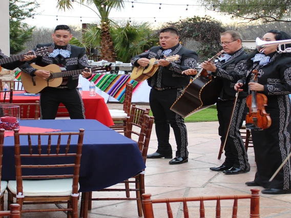 A mariachi band playing before a crowd of people at picnic tables.