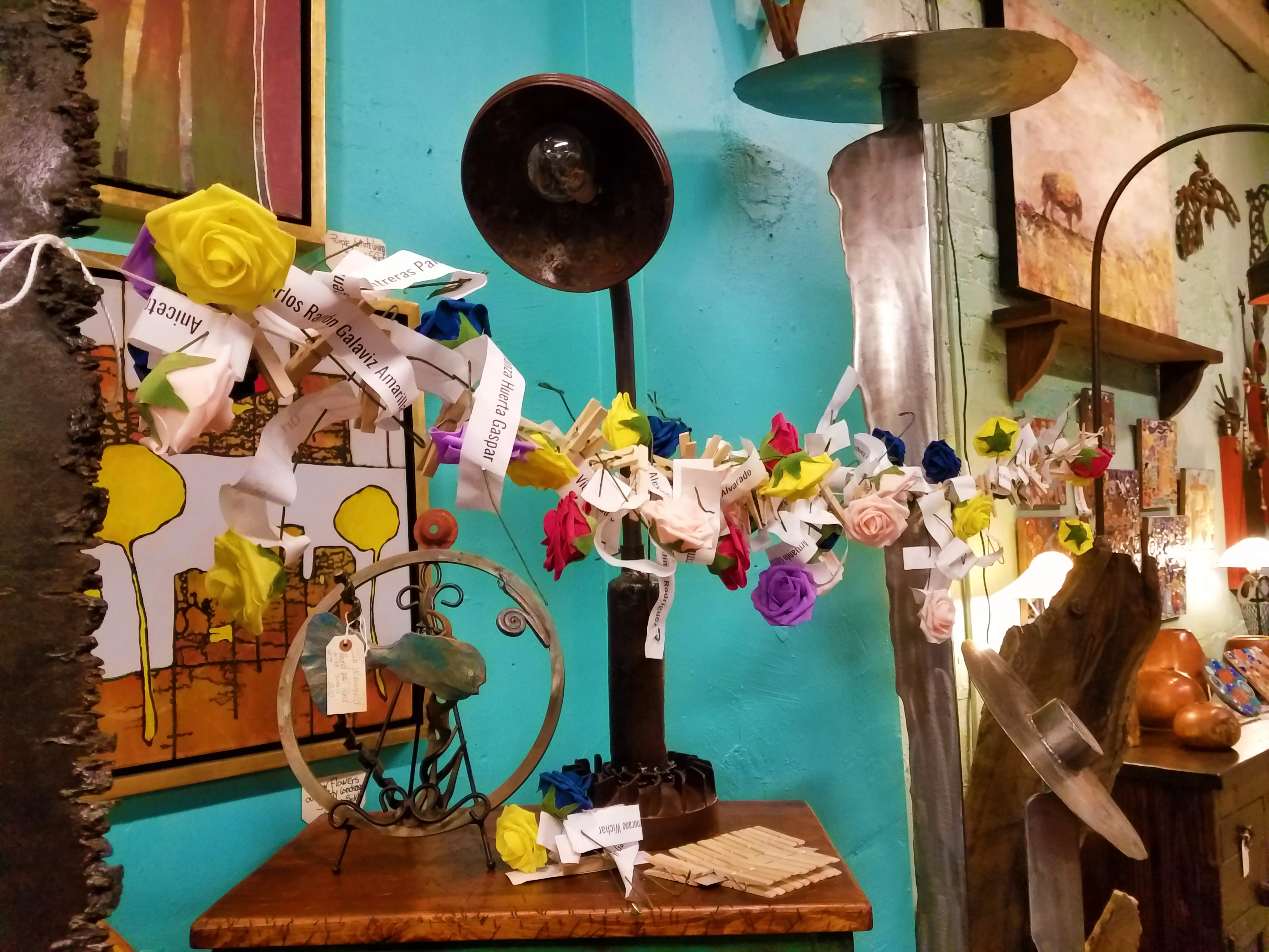 An art piece constructed of yellow and purple roses strung across a line with notes dispersed within them