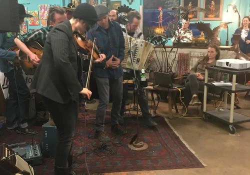 A man passionately playing a violin or viola, he leans into it as he slides his playing arm up the neck of the violin or viola.