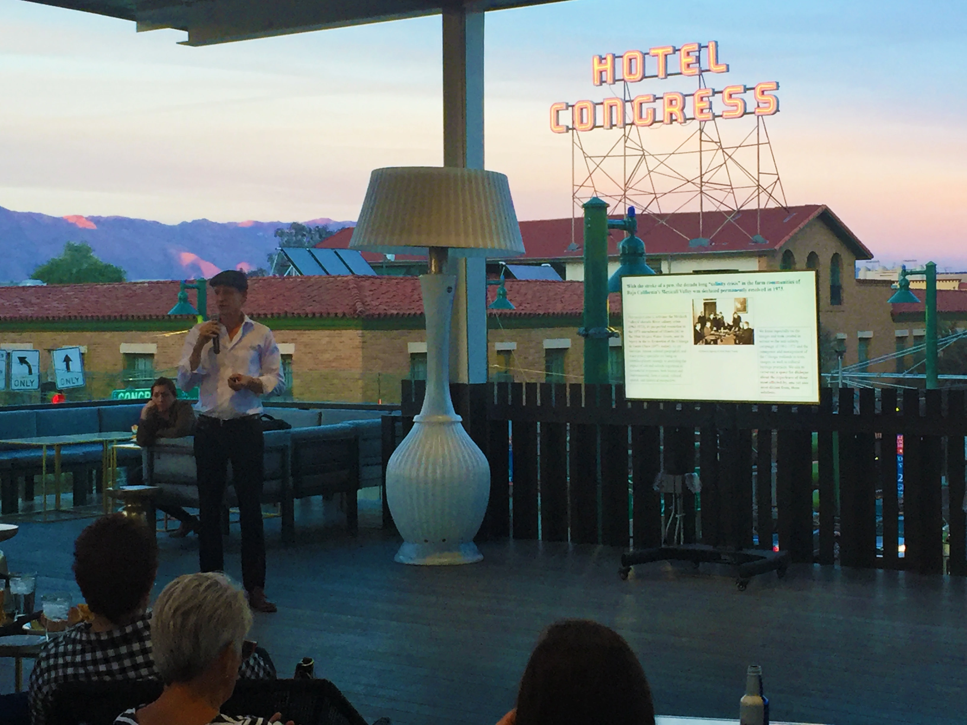 Hotel Congress neon sign above and behind a projection screen with a message about borders